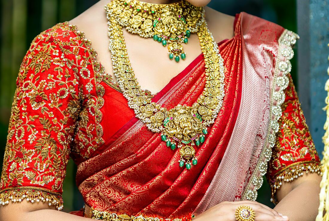 Bride in a hand-embroidered red bridal blouse and silk saree