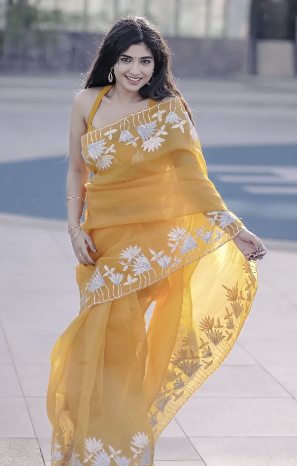 Woman in a mustard organza saree with hand-embroidered floral borders