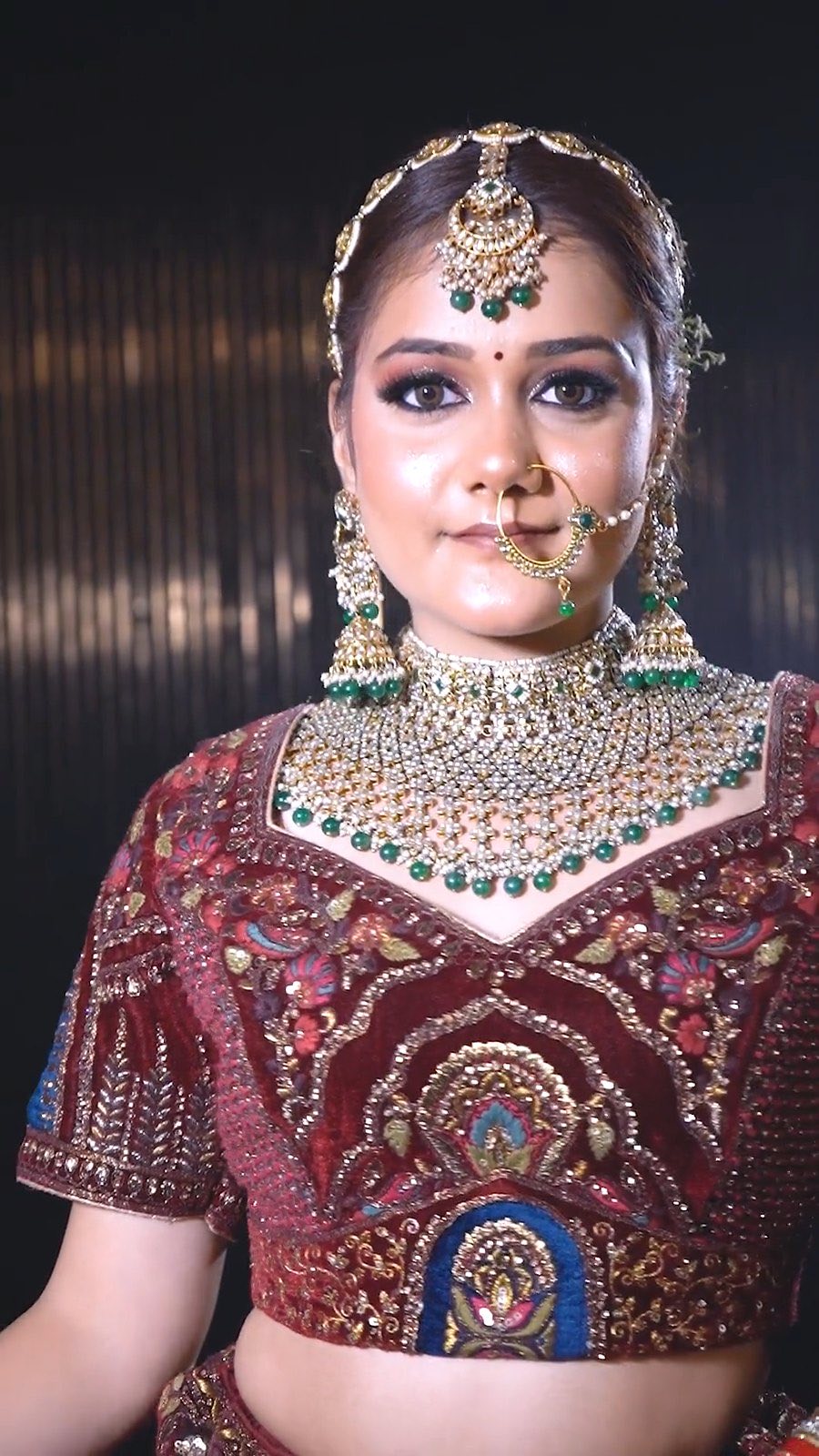 Maroon bridal blouse with dense multicolour embroidery, worn with kundan jewellery